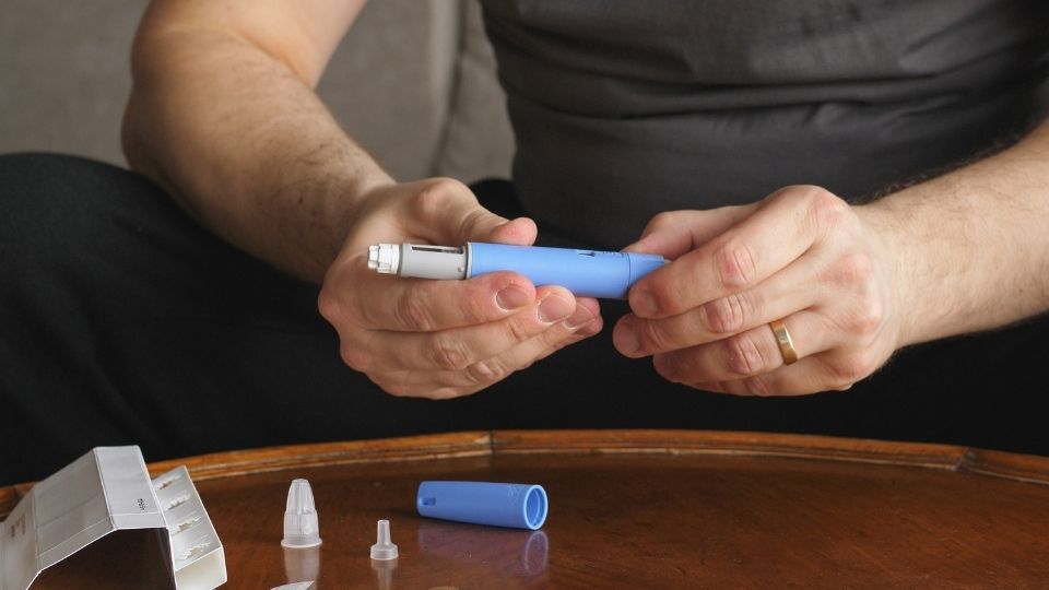 The Difference Between Semaglutide and Tirzepatide a man thinks while assembling an injection device