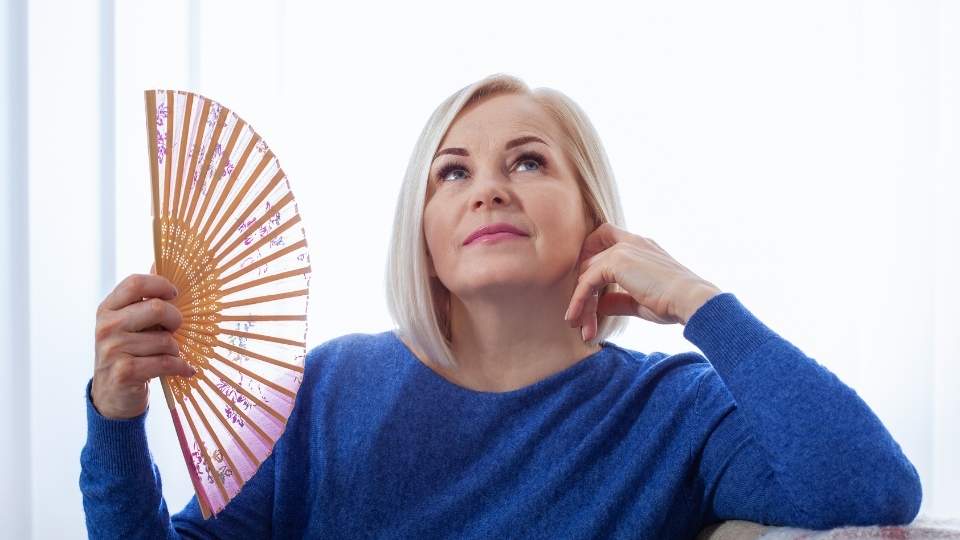 What Are the First Signs of Perimenopause a woman fans herself due to a hot flash.