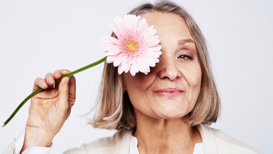 What Signals the End of Menopause hero image of a woman holding a flower.